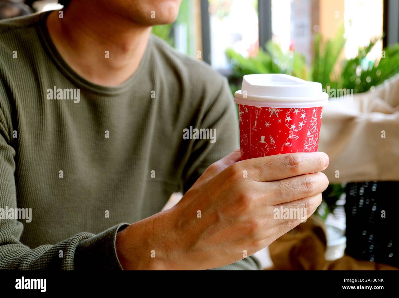 Giovane uomo tenendo un rosso e bianco da asporto tazza di caffè in mano Foto Stock