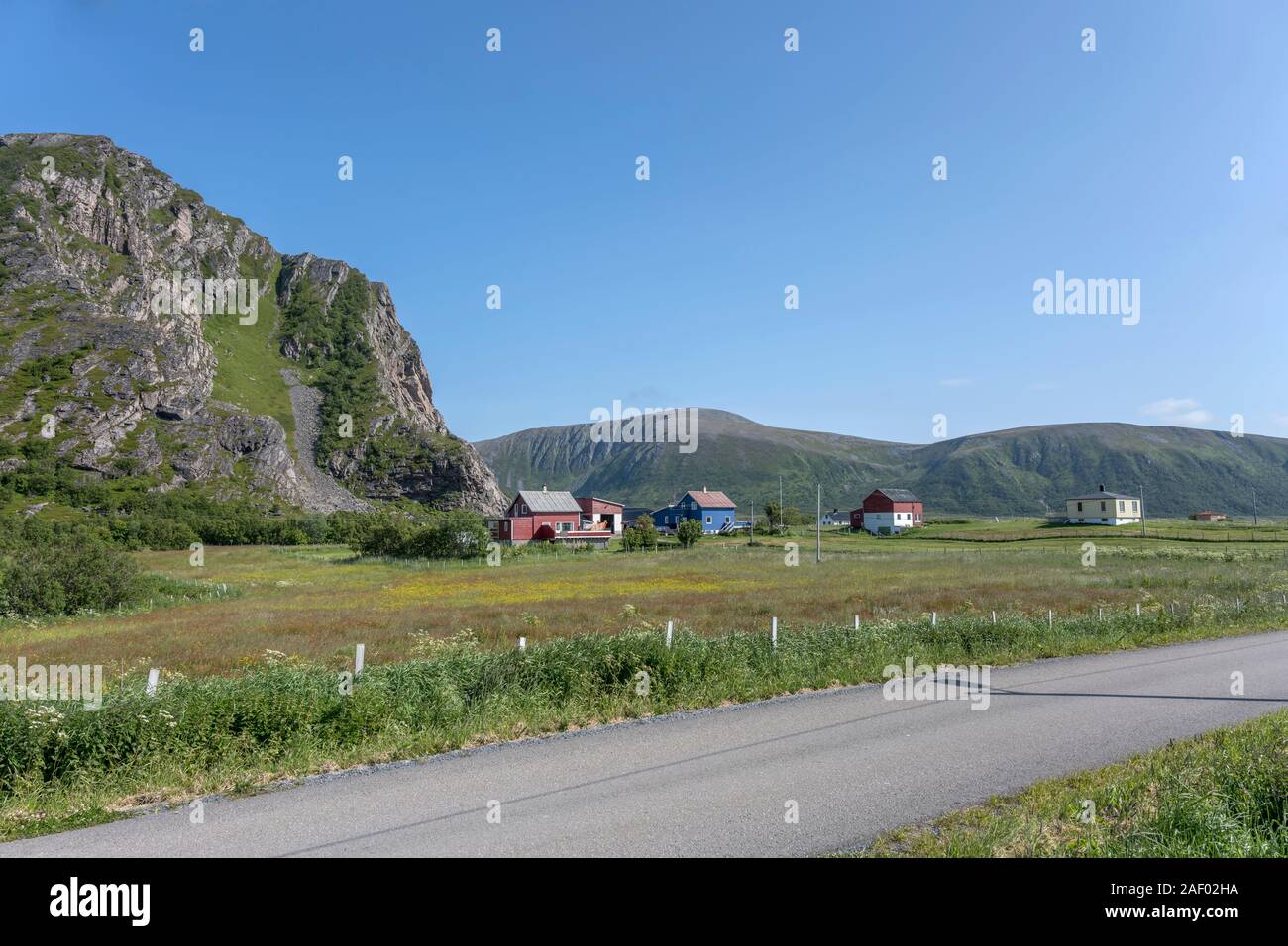 Paesaggio con la roccia ripida collina e distanziati case di villaggio sul lato occidentale dell'isola, girato sotto la luminosa luce estiva a doga, Andoya, Vesteralen Foto Stock