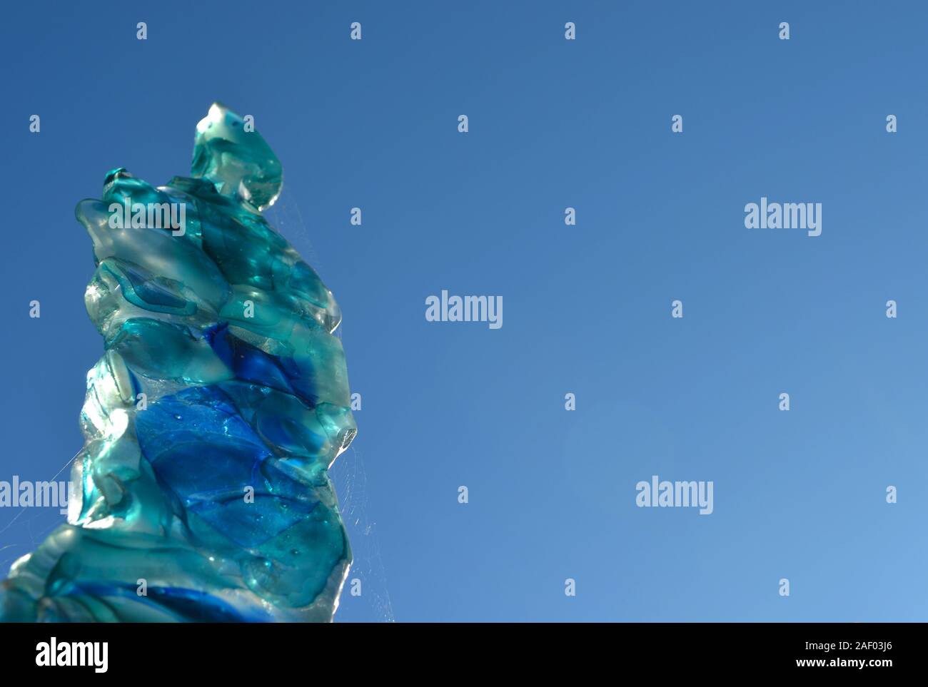 Statua di cristallo con trasparenza e riflessi di luce.Blue sky sfondo . Effetti irreale. Foto Stock
