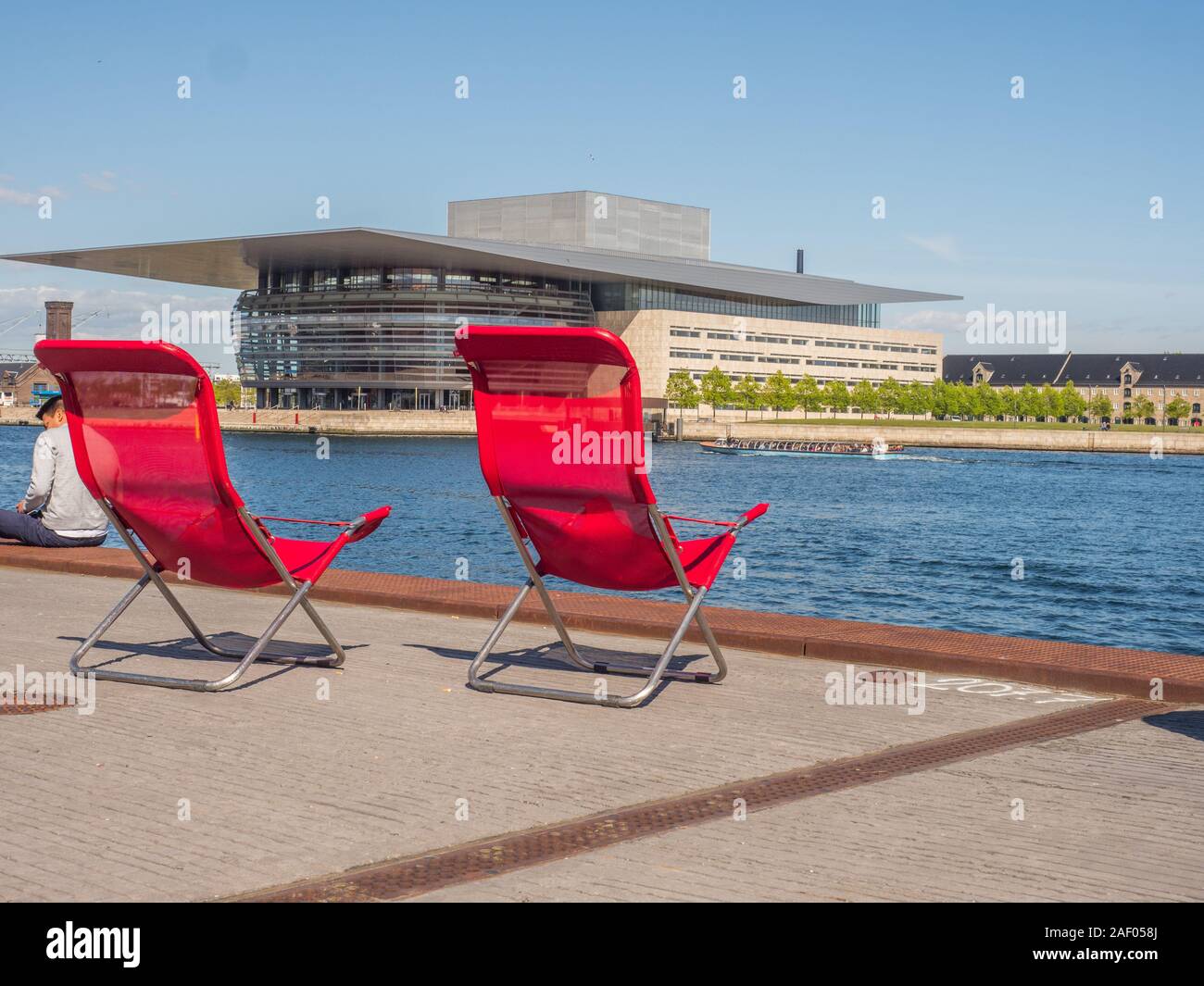 Copenhagen, Danimarca - 26 Aprile 2019: Rosso lettini con Copenaghen Opera House in background. Isola di Holmen Foto Stock