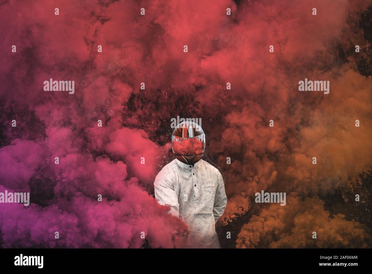 Guy in maschera in piedi tra rosa, viola e arancione fumo bombe Foto Stock
