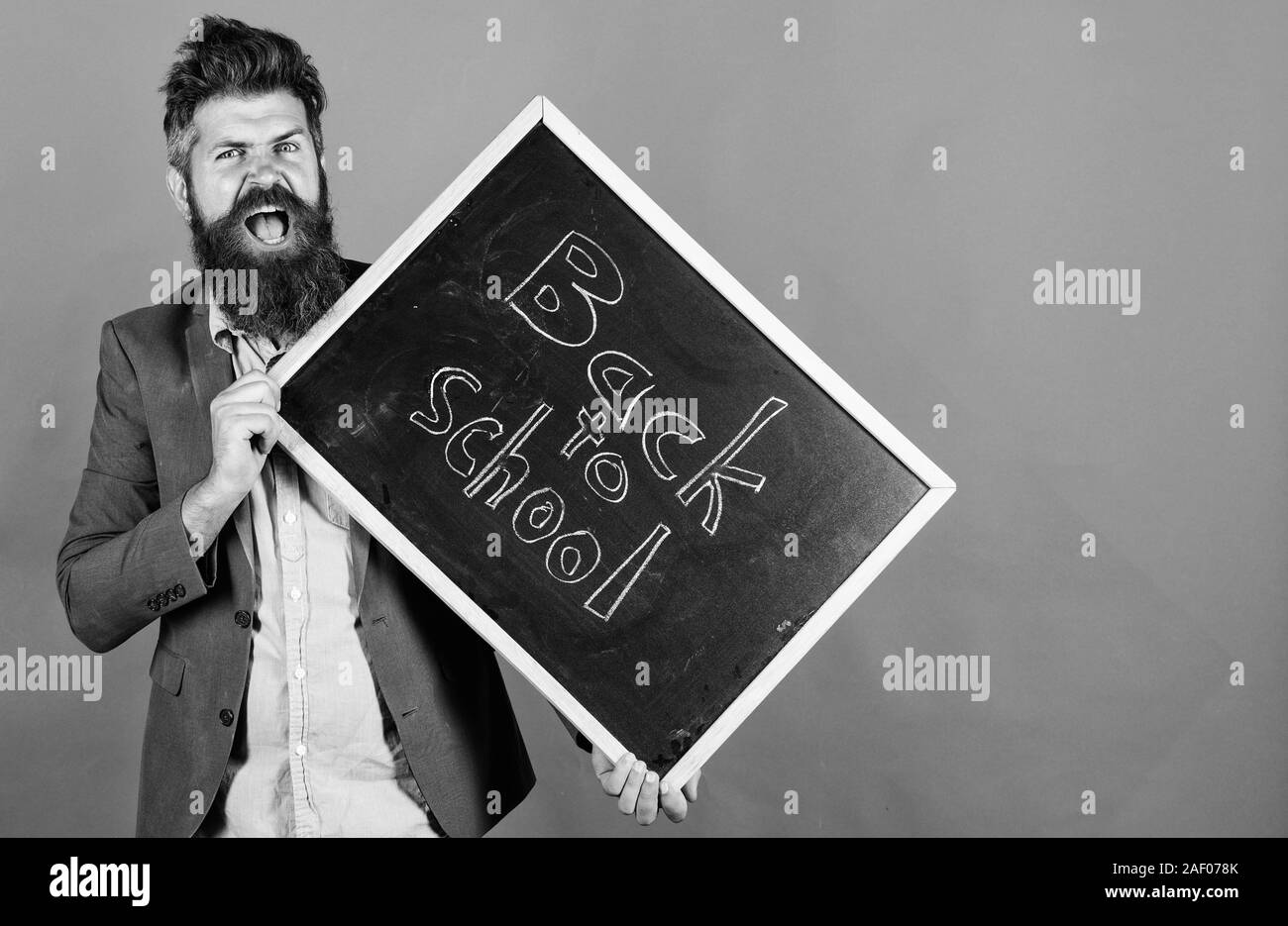 Insegnamento occupazione stressante. Insegnante con capelli tousled stressante circa anno scolastico inizio. Rimanere positivo. Insegnante uomo barbuto detiene blackboard con iscrizione torna a scuola lo sfondo rosso. Foto Stock