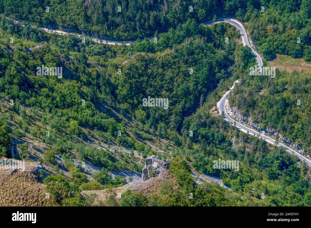 Una tortuosa strada di montagna attraverso i boschi in condizioni estreme di alta quota. Foto Stock