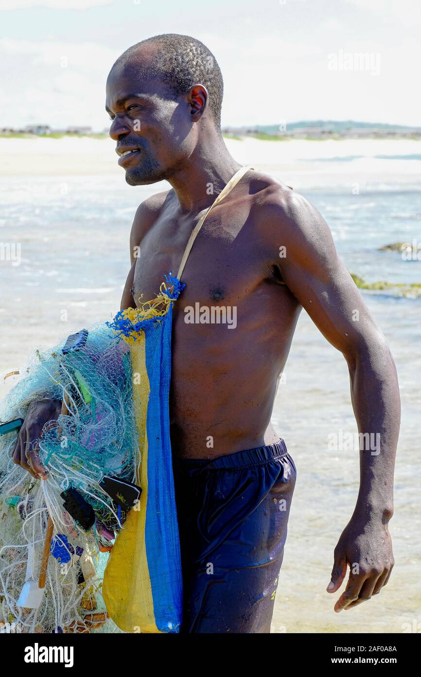 Pescatore africano lasciando la spiaggia con la sua rete da pesca Foto Stock
