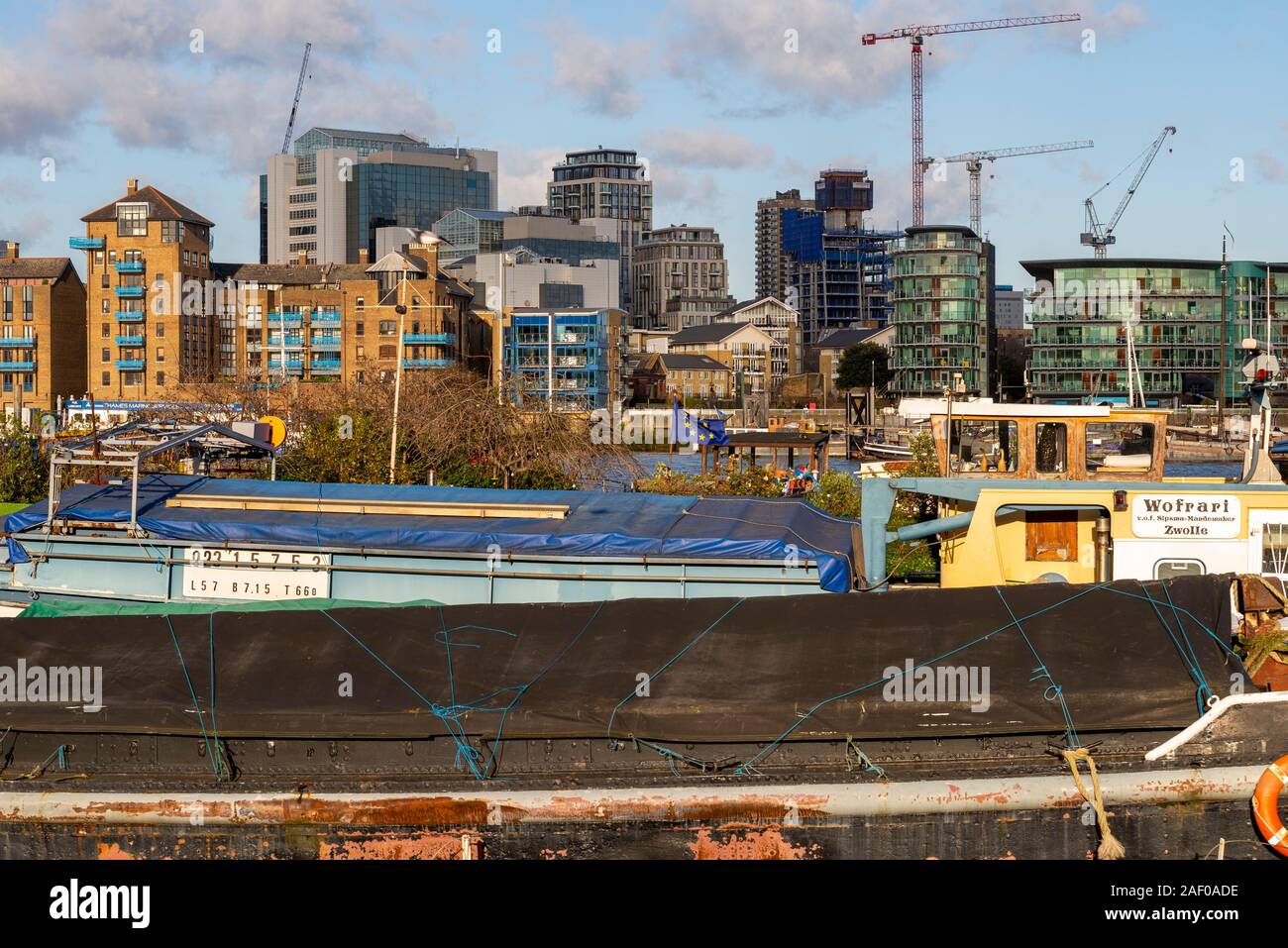 Barche e chiatte ormeggiate presso il Tower Bridge posti barca presso Downings strade sul Fiume Tamigi. Wofrari Zwolle. Il lungofiume di moderni sviluppi a Wapping Foto Stock