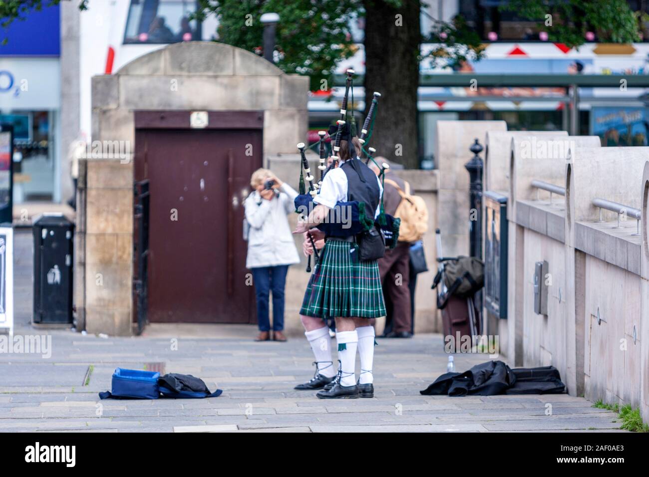 Turistica prendendo foto a un busker cornamuse nel Royal Scottish Academy, il tumulo, Edimburgo, Scozia, Regno Unito Foto Stock
