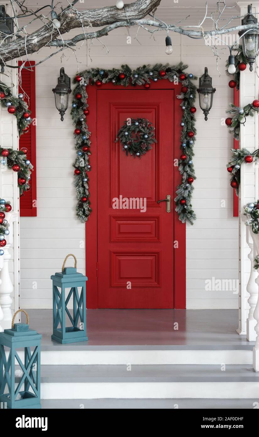 Decorate porta rossa per le vacanze di Natale con lanterne blu sulle scale. Foto Stock