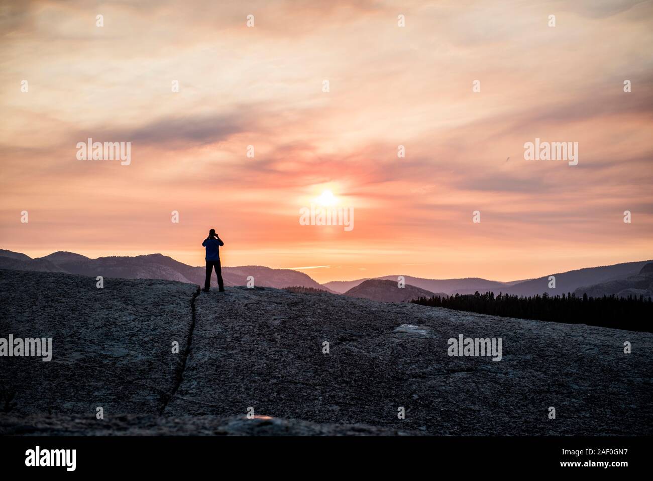 L'uomo stagliano contro il tramonto in montagna Foto Stock
