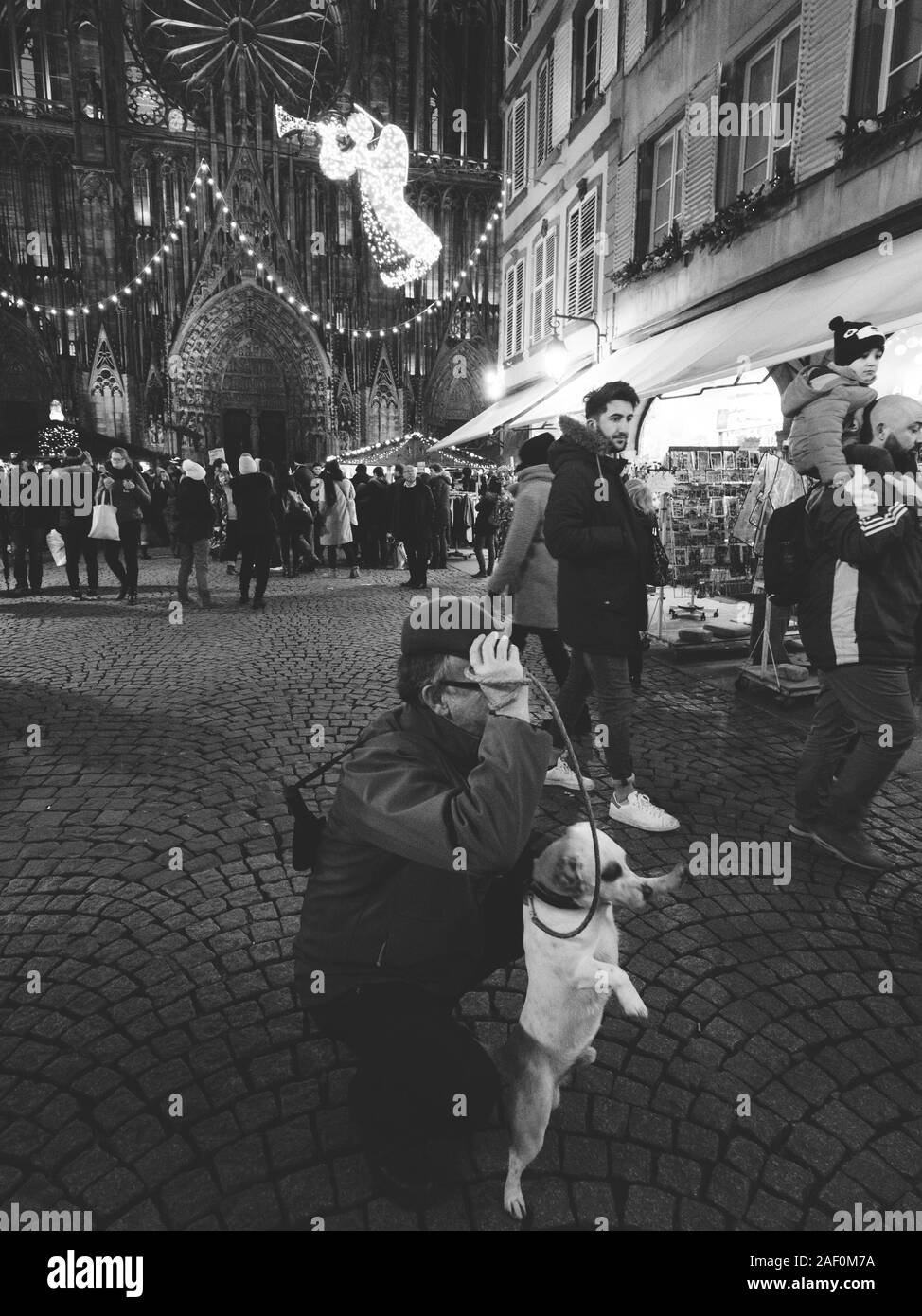 Strasburgo, Francia - Dic 24, 2018: immagine in bianco e nero di un uomo con un simpatico cane che posano per una foto davanti alla Cattedrale di Notre Dame de Strasbourg catherdral Mercatino di Natale Foto Stock