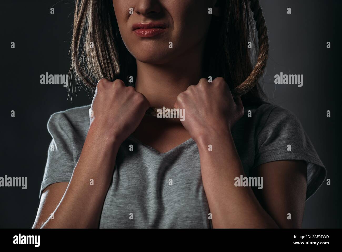Vista ritagliata della depressione, gridando donna mettendo cappio sul collo su sfondo nero Foto Stock