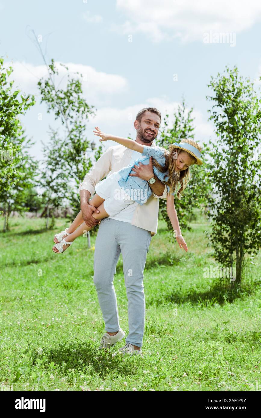Padre Felice Tiene in armi allegro figlia nel cappello di paglia Foto Stock