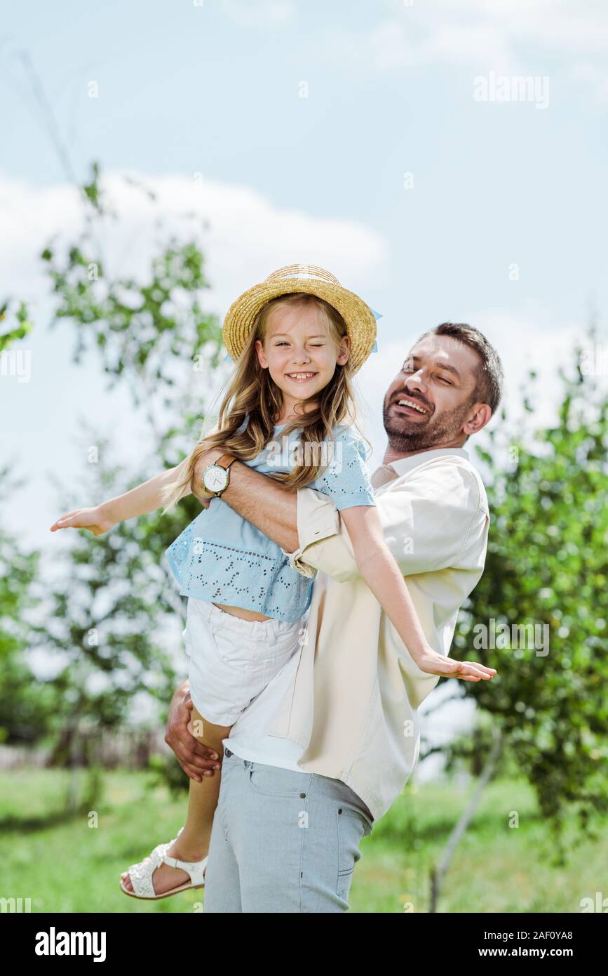 Felice barbuto padre tenendo in armi curare figlia guardando la fotocamera Foto Stock