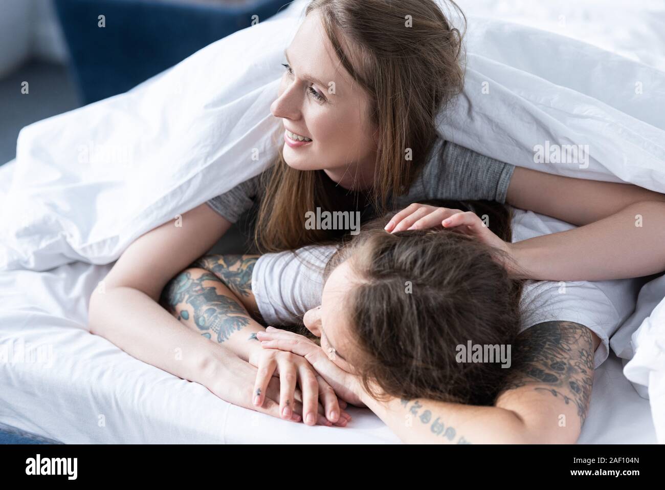 Due lesbiche sorridente abbracciando mentre giacente sotto la coperta a  letto Foto stock - Alamy