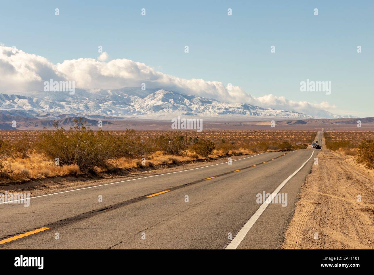 Una autostrada e montagne innevate nel tardo autunno nel deserto di Mojave e la San Bernardino Mountains, nel sud della California, Stati Uniti d'America. Foto Stock