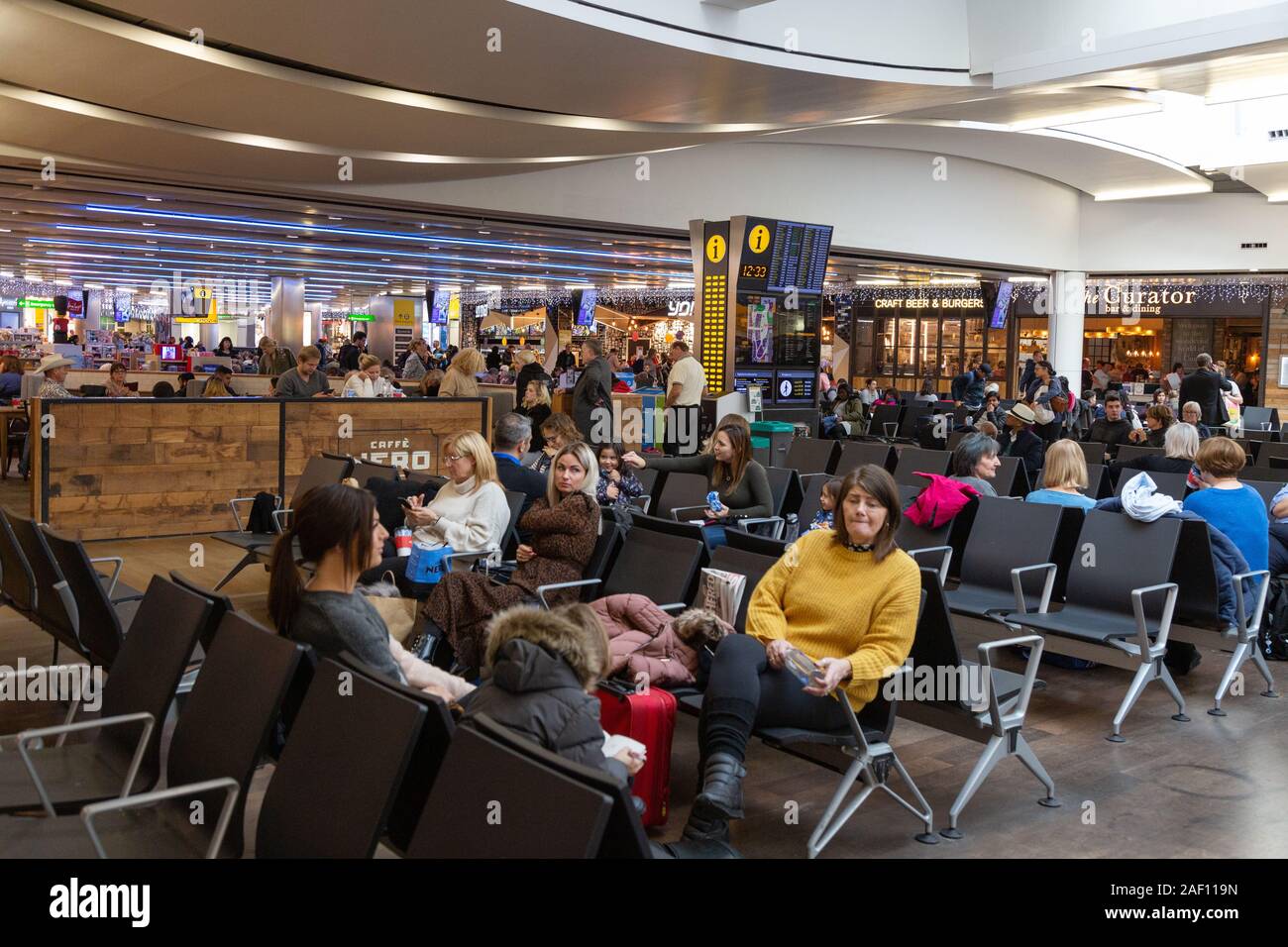 Aeroporto di heathrow Londra UK; terminale 3 interno; i passeggeri seduti in attesa per i loro voli, Heathrow London REGNO UNITO Foto Stock