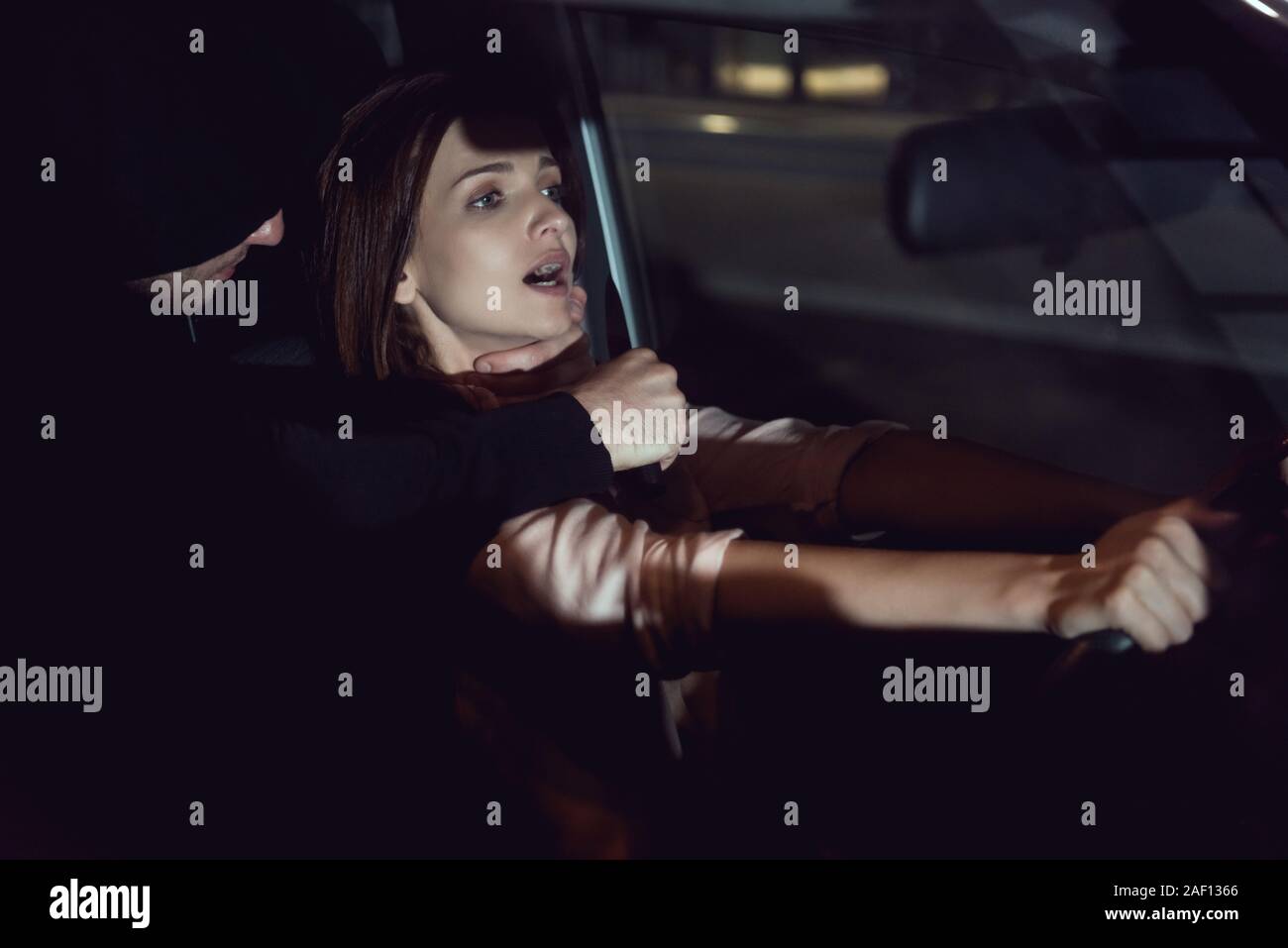 Ladro soffoca la bella donna spaventati in automobile di notte Foto Stock