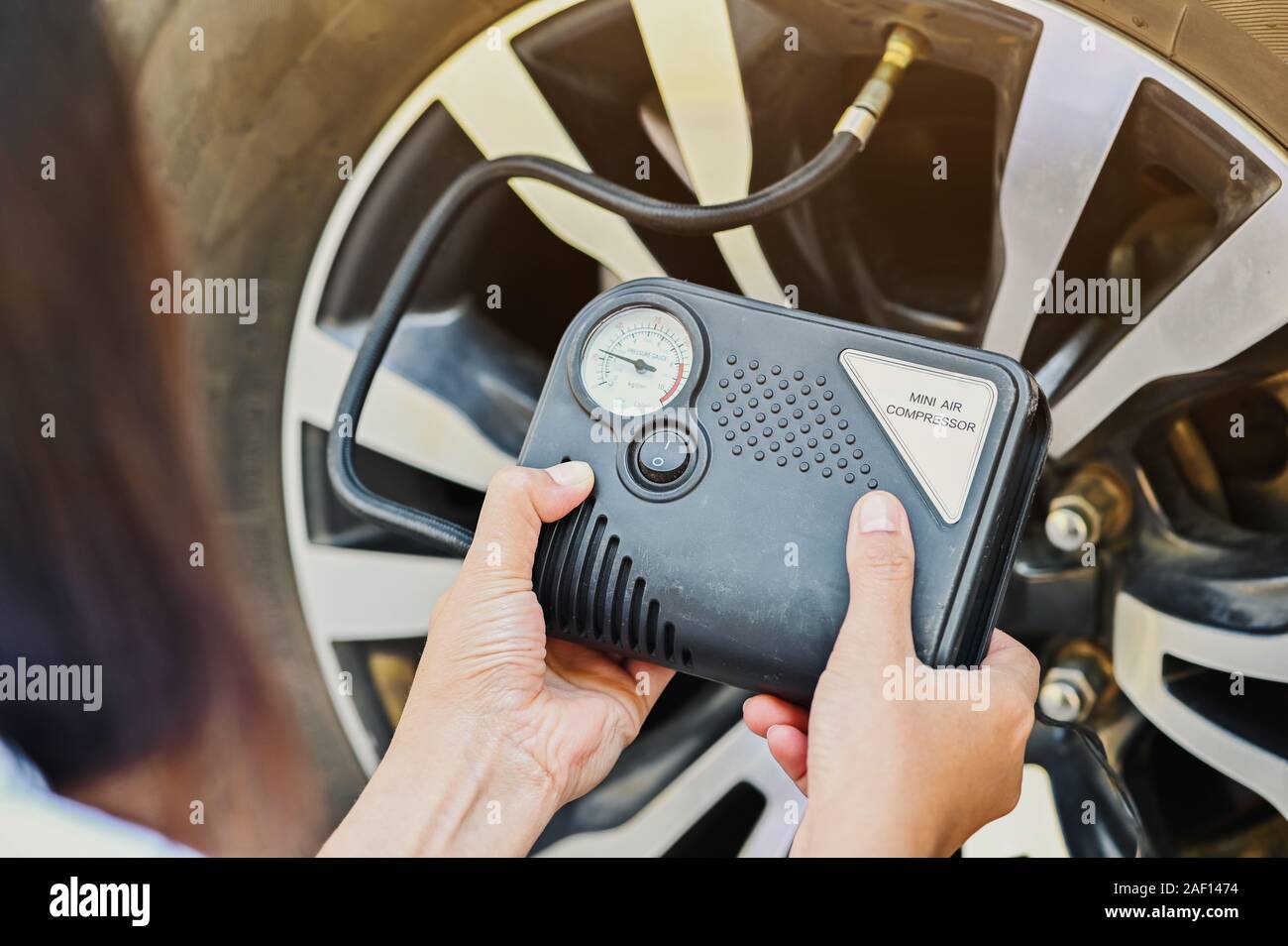 Le donne il gonfiaggio di pneumatici con un'emergenza mini compressore aria  auto quando le perdite del pneumatico mentre si è in viaggio Foto stock -  Alamy