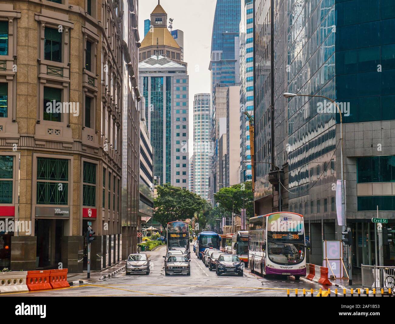 Il traffico si è fermato a una luce di colore rosso su Robinson Road a Singapore's downtown core business, circondato da grattacieli su entrambi i lati. Foto Stock