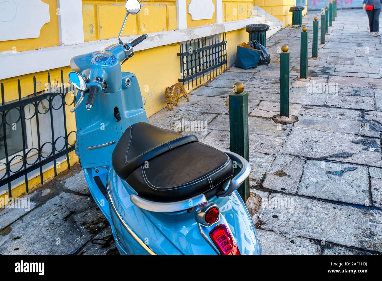 Un disperso tabby cat passeggiate fino ad un blu moto scooter nel quartiere Plaka di Atene in Grecia. Foto Stock