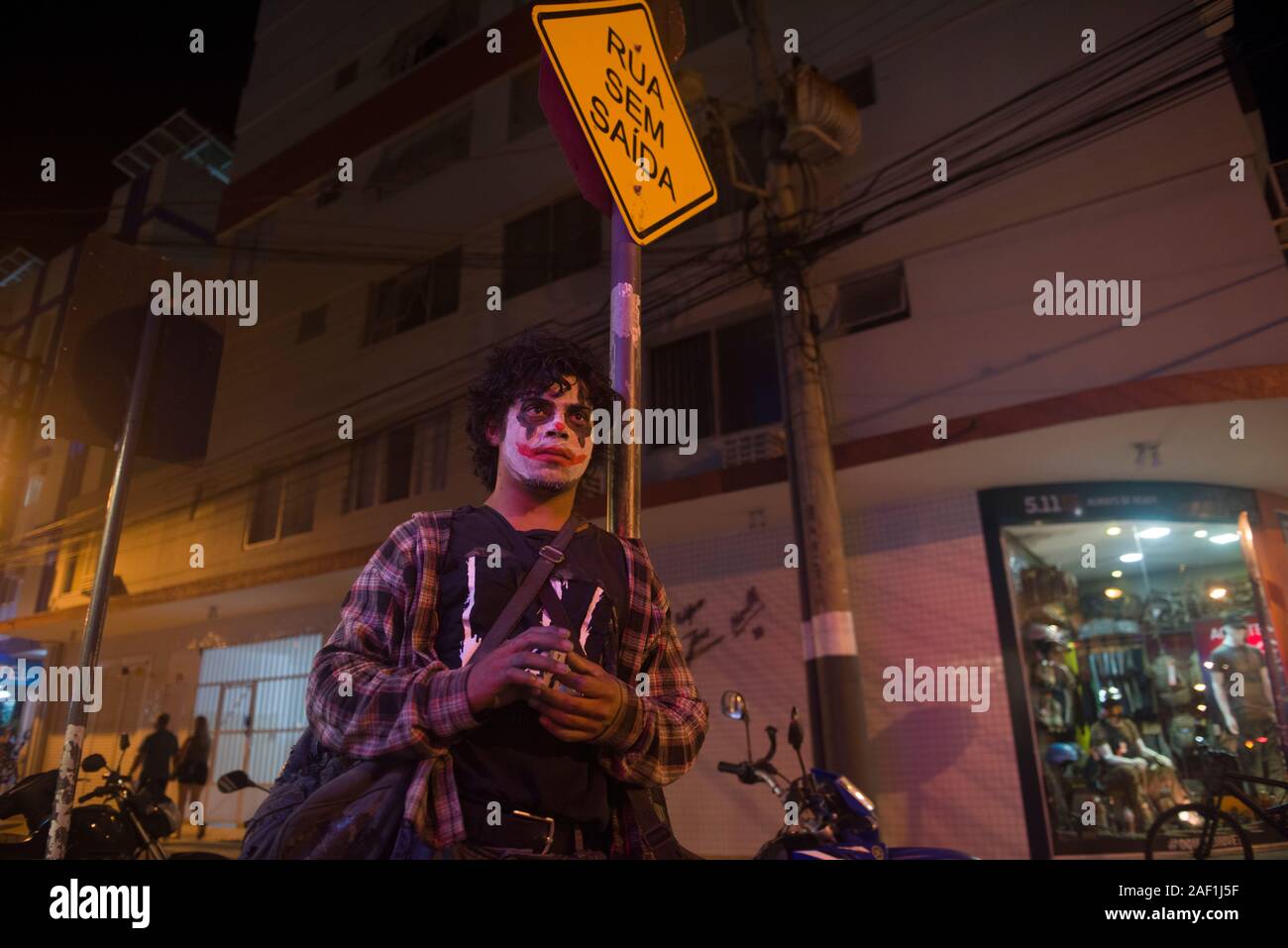 Balneario Camboriu, Santa Catarina, Brasile - 16 Novembre 2019: locale giovane artista di strada con Joker costume in un angolo di strada di strada trafficata Foto Stock