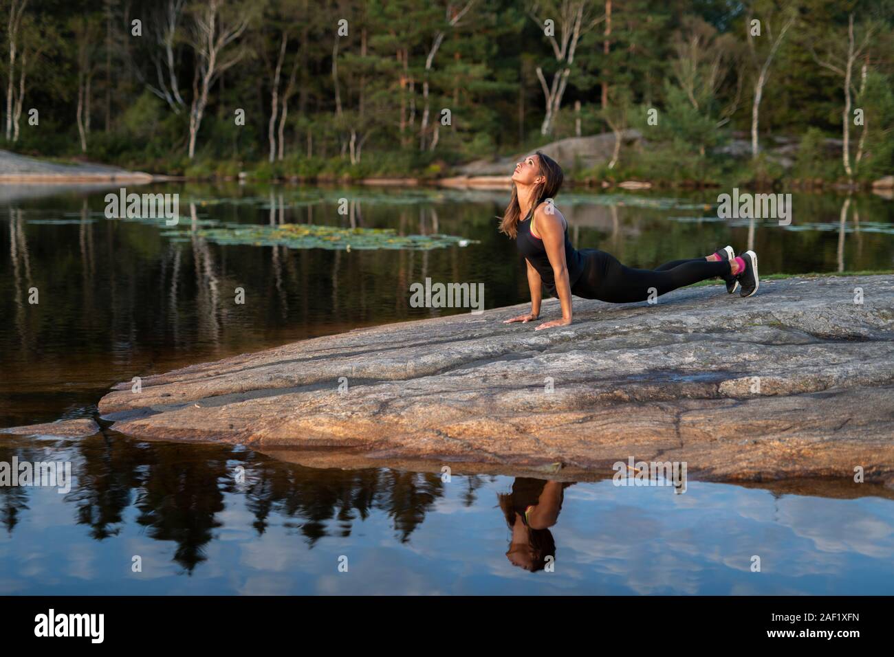 Donna al lago facendo yoga Foto Stock