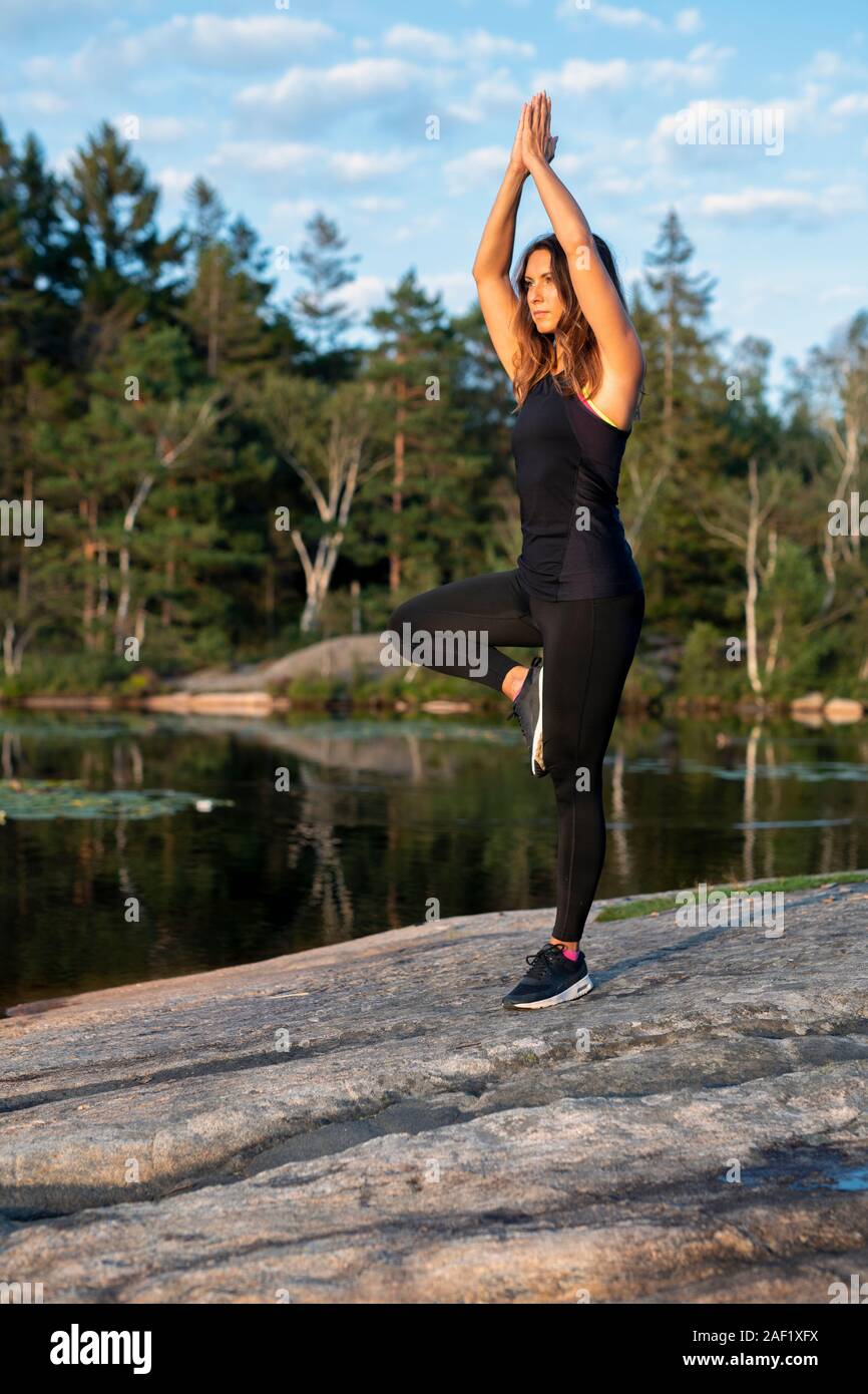 Donna al lago facendo yoga Foto Stock