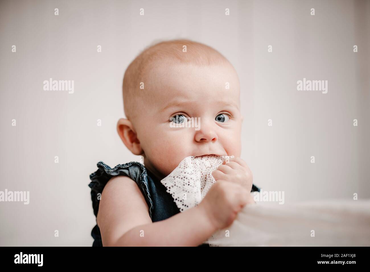 Baby girl contenimento di materiale nella bocca Foto Stock