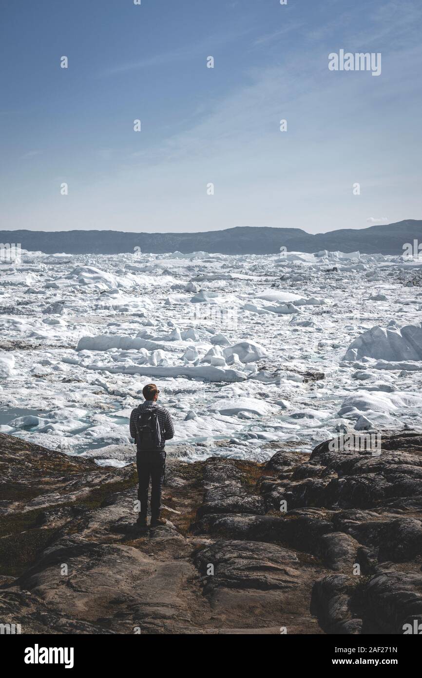 La gente seduta in piedi di fronte del ghiacciaio enorme muro di ghiaccio. Icebergs Ilulissat. Jakobshaven Eqip Sermia Glacier ghiacciaio di Eqi Sermia in Groenlandia chiamato Foto Stock
