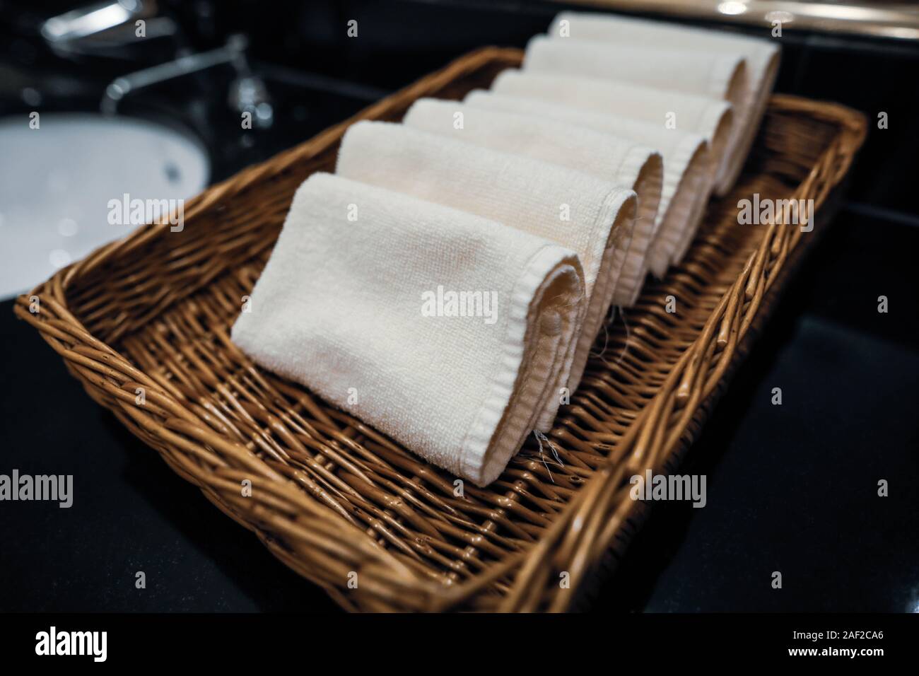 Profondità di campo (messa a fuoco selettiva) immagine con un panno piccoli asciugamani in un cestello di legno in un bagno di hotel. Foto Stock