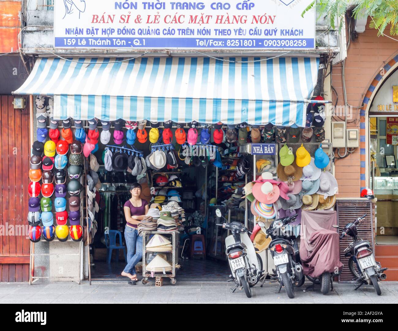 La città di Ho Chi Minh, Vietnam - 29 Ottobre 2013: Donna al di fuori di un cappello shop. Il vietnamita le donne piace indossare cappelli alla protezione contro il sole. Foto Stock