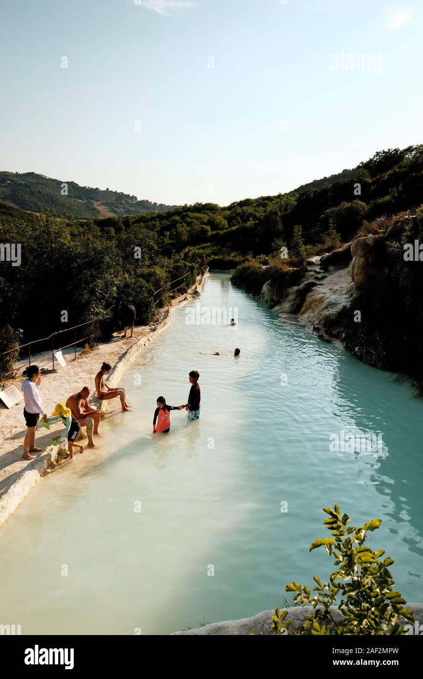 Visitatori godendo il pubblico gratuito piscina di acqua termale dell'antico villaggio termale di Bagno Vignoni, Val d'Orcia Toscana Italia EU Foto Stock