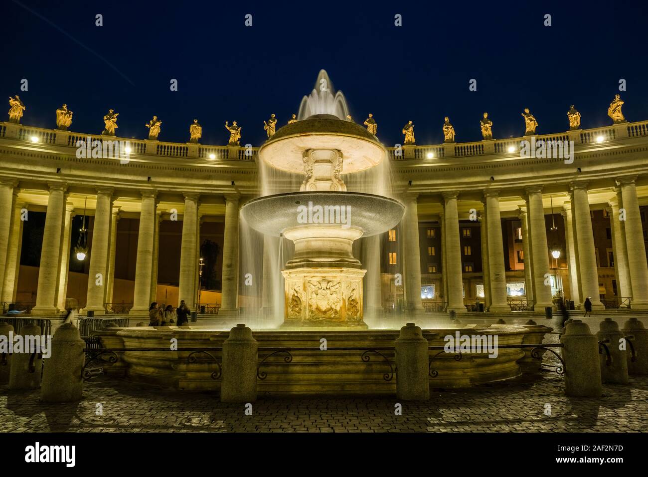 Il pozzo Fontana del Vaticano, costruita da Gian Lorenzo Bernini, situata sulla piazza di San Pietro, illuminata di notte Foto Stock