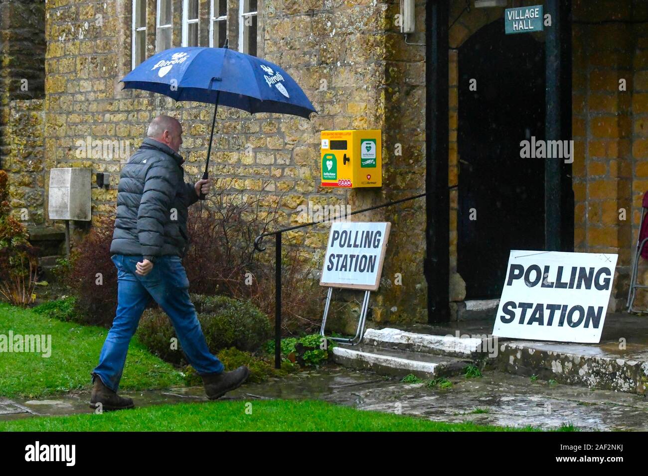 Walditch, Dorset, Regno Unito. Il 12 dicembre 2019. Un uomo con un ombrello arrivando sotto la pioggia a votare al seggio a Walditch nel Dorset su un generale bagnato il giorno delle elezioni. Credito Foto: Graham Hunt/Alamy Live News Foto Stock