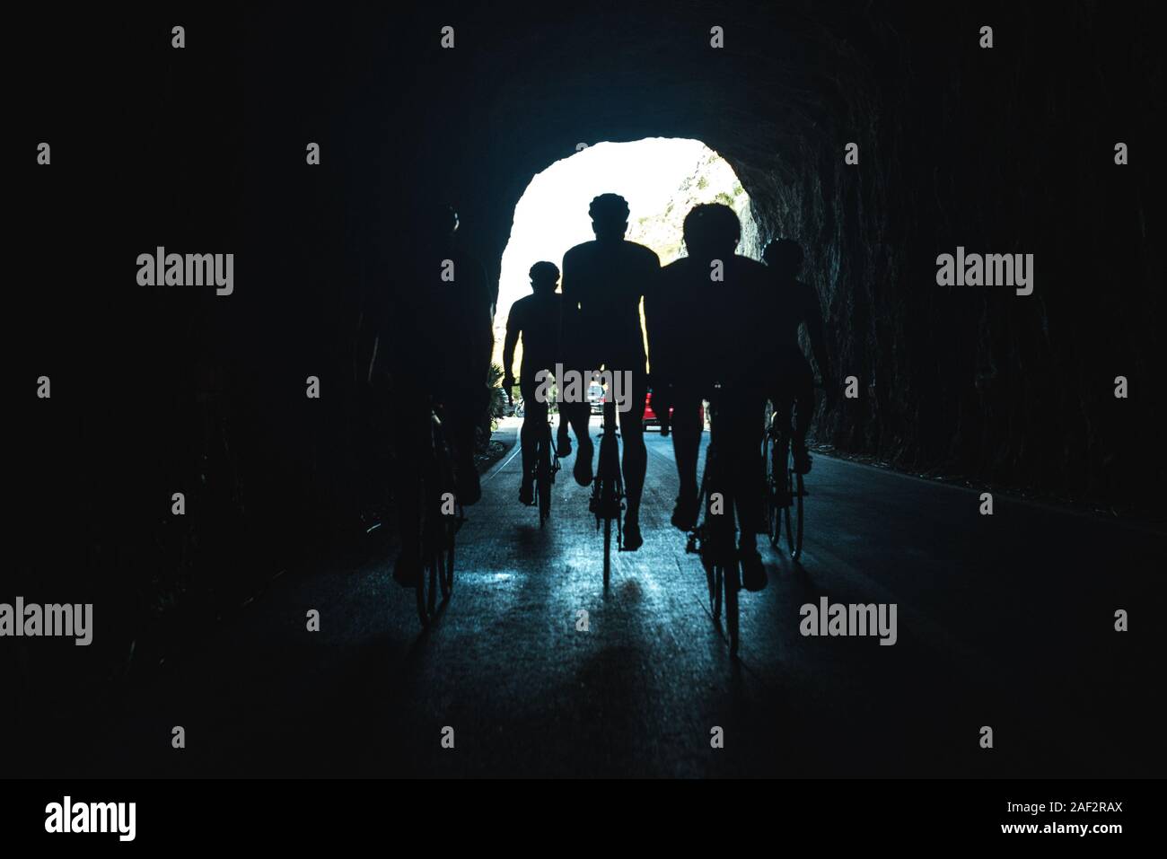 Silhouette di atleti sulla bicicletta nel buio del tunnel Foto Stock
