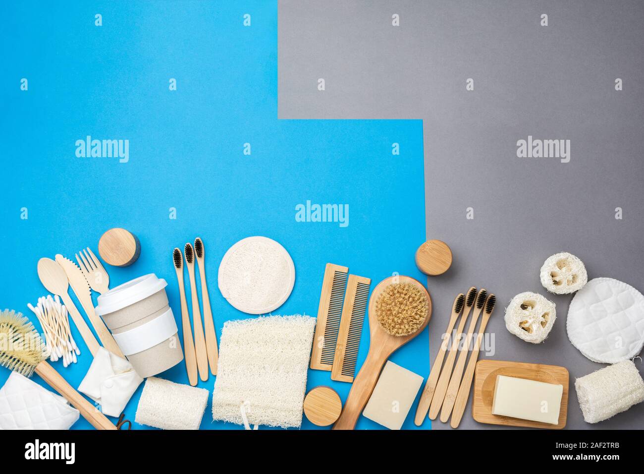Rifiuti Zero eco friendly prodotti per la cura personale delle spazzole in legno, bambù spazzolini da denti, la Luffa, saponi naturali, riutilizzabile tazza di caffè sulla colorata blu grigio sfondo, il fuoco selettivo Foto Stock