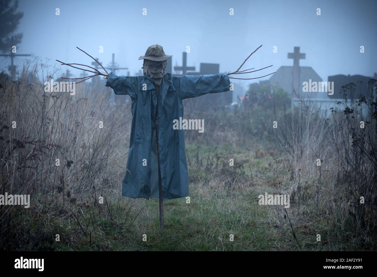 Terribile spaventapasseri nel manto scuro e sporco hat sorge isolato su un cimitero sfondo. Concetto di Halloween Foto Stock