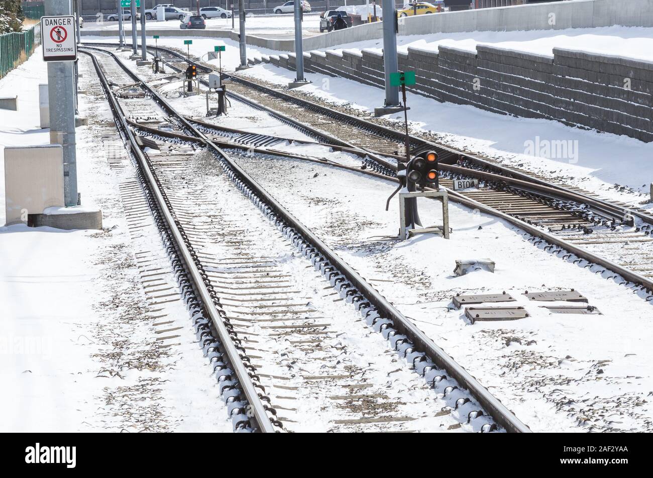 Interruttori alond coperta di neve di binari ferroviari che corre parallelo alla strada in una fredda soleggiata giornata winnter Foto Stock