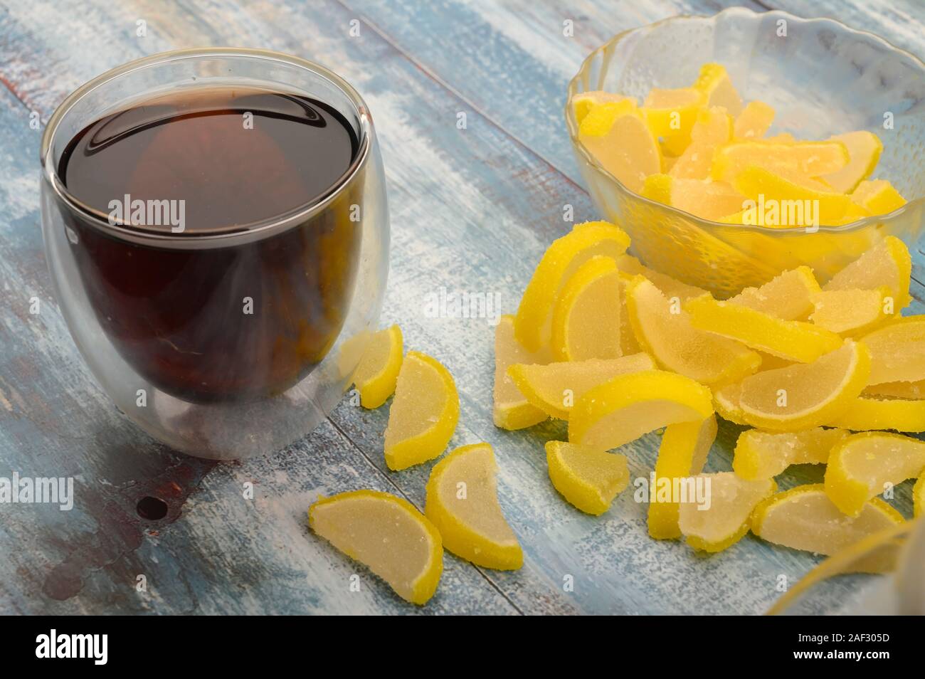 La marmellata di arance le fette di limone e un bicchiere di tè nero su uno sfondo di legno. Dolce con. Close up Foto Stock