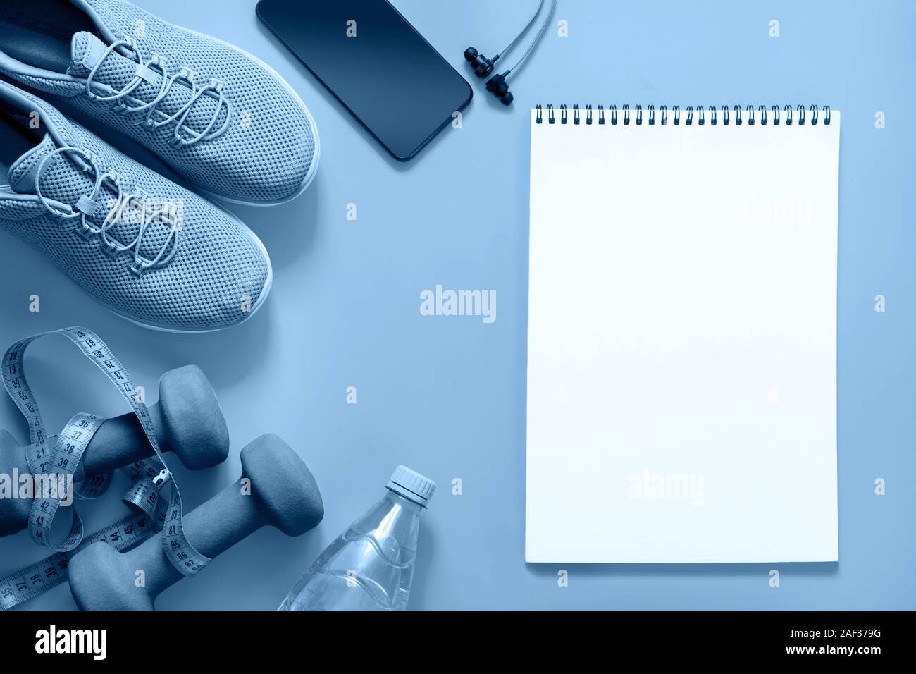 Sport e attrezzature per il fitness con le scarpe da ginnastica e cuffie sul blu classico. Vuoto con spazio per il testo. Vista da sopra. Colore alla moda Classic indizio del Foto Stock