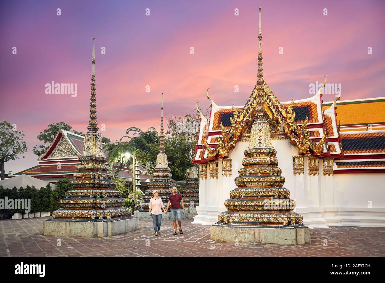 Famiglia giovane coppia camminare vicino a golden Chedi del Wat Pho tempio a Bangkok, in Thailandia Foto Stock