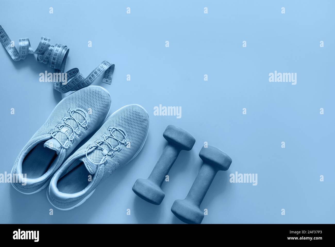 Sport e attrezzature per il fitness, pesi, fitness scarpe, nastro di misurazione sul blu. Vista fron sopra, lo spazio per il tuo testo. Colore alla moda Classic indizio del Foto Stock