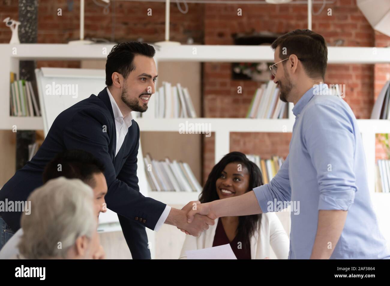 Medio Oriente aspetto e imprenditori caucasica si stringono la mano durante la riunione Foto Stock