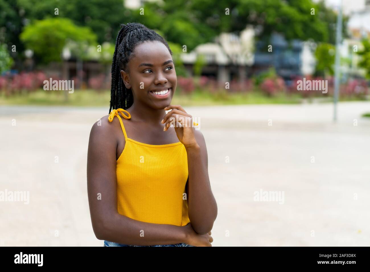 Bella americano africano donna con dreadlocks all'aperto in estate in città Foto Stock