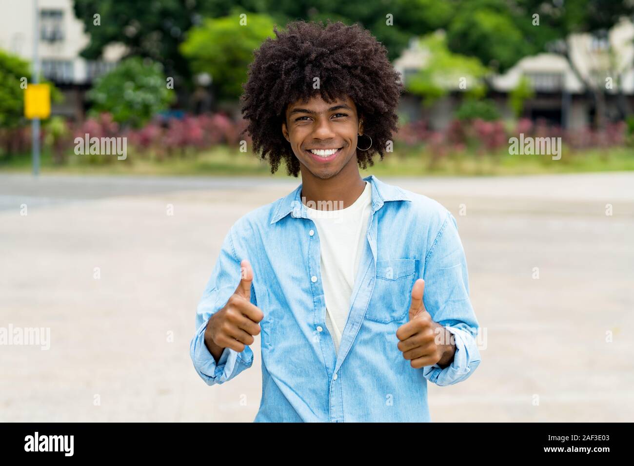 Felice African American hipster giovane adulto che mostra i pollici fino all'aperto in estate in città Foto Stock