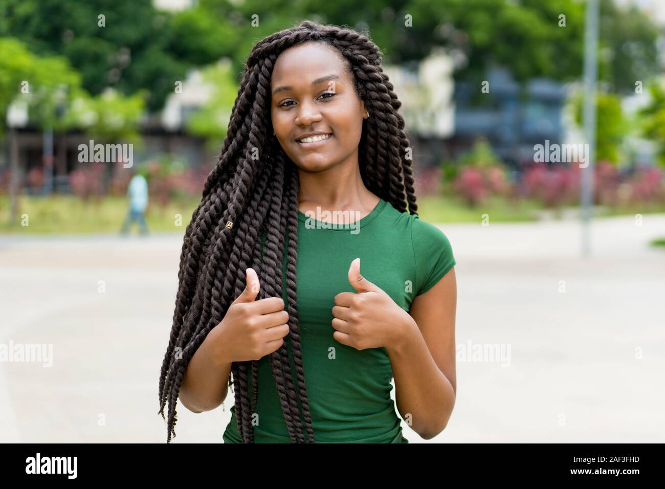 Felice americano africano giovane donna adulta con fantastica pettinatura all'aperto in estate in città Foto Stock