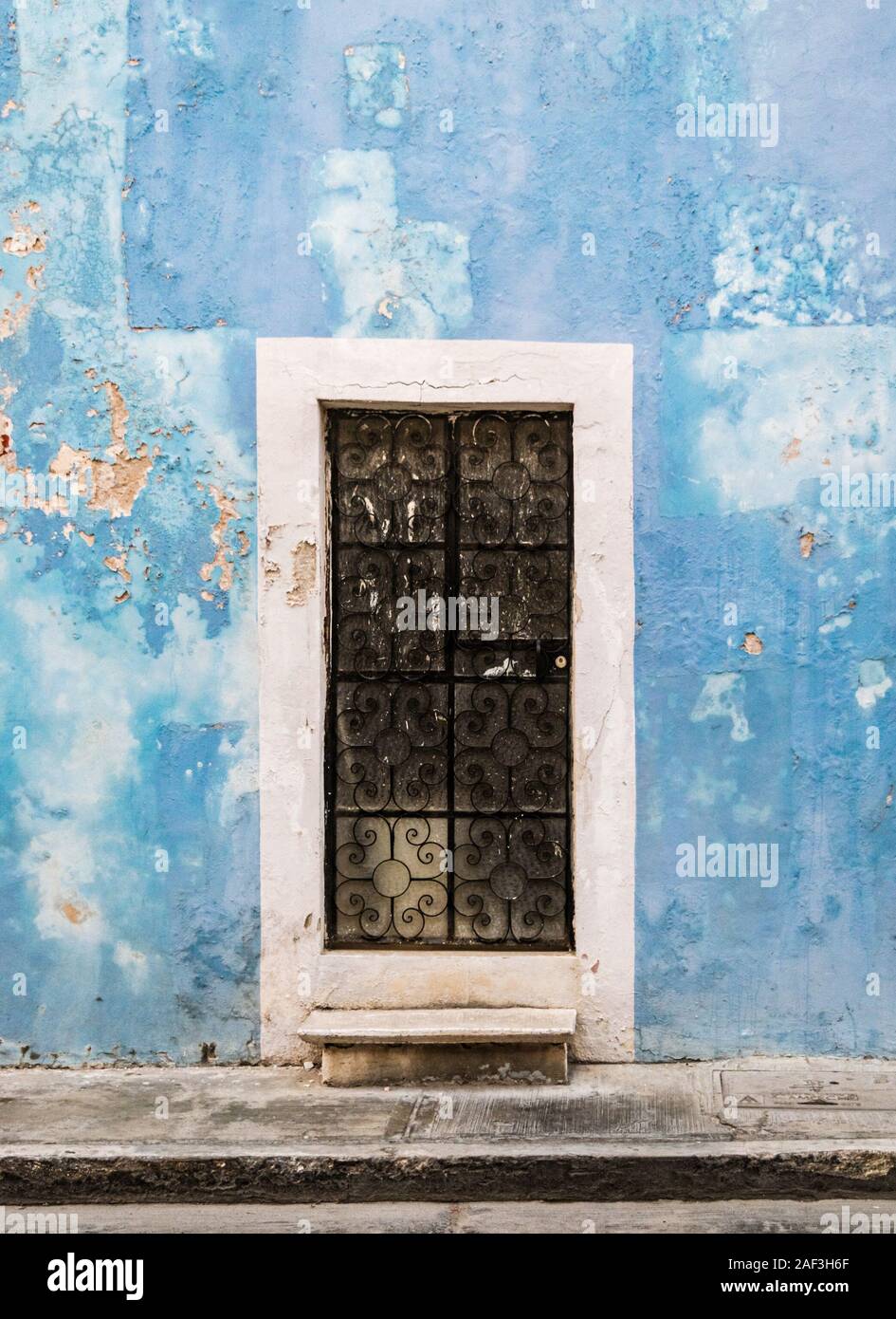 Sbiadito, run-blu verso il basso muro di un edificio coloniale nel bisogno di un rinnovo in Campeche, Yucatan, Messico. Foto Stock