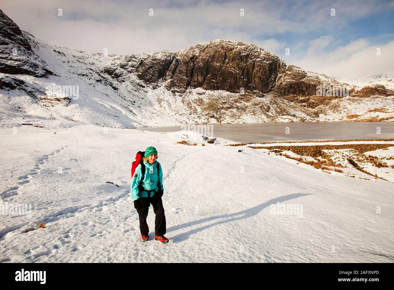 Una donna hill walker da un congelati Stickle Tarn in Langdales, Lake District, REGNO UNITO Foto Stock