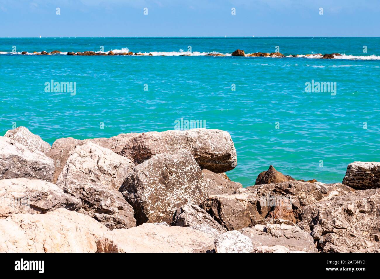 Pietre massicce rocce sdraiato sulla spiaggia come un confine tra la spiaggia ghiaiosa spiaggia del Frate e del mare Adriatico onde e flussi. Rocky marina come una breakw Foto Stock