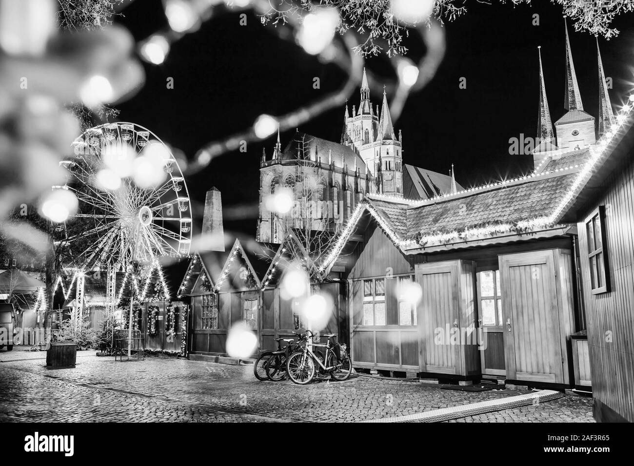 Astratto foto di festa con luci sfocate. Mercato di Natale, ruota panoramica Ferris e famosa cattedrale Dom collina di notte. Erfurt, Germania. In bianco e nero Foto Stock