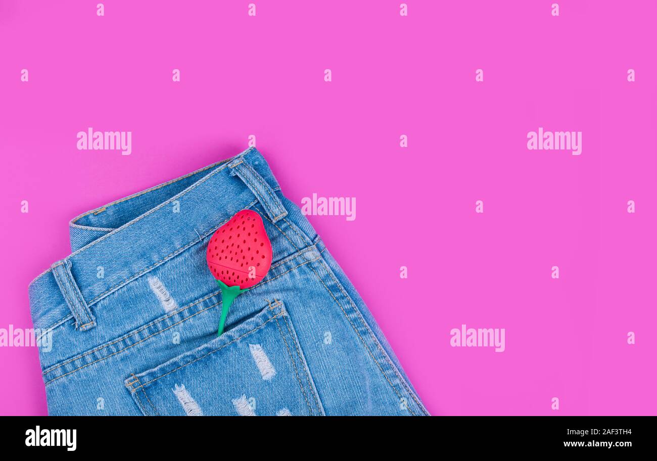 Moda denim shorts con fragole nella tasca posteriore contro un sfondo rosa. Foto Stock